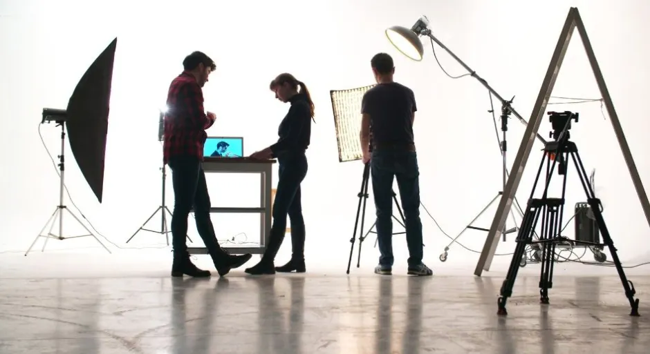 Three individuals in a photography studio session utilizing professional lighting and camera gear.
